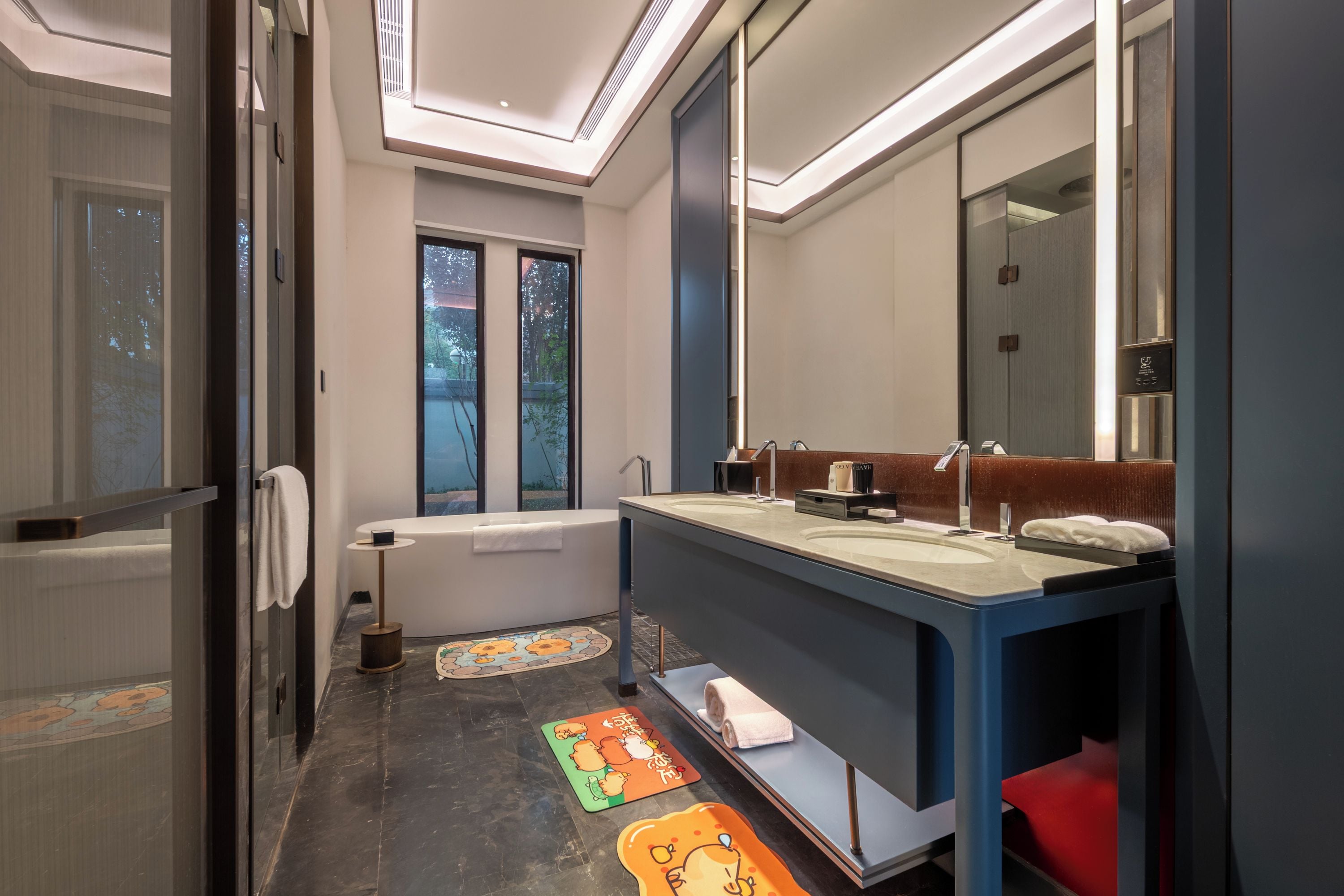 Un baño moderno con bañera, un espejo grande y un tocador con lavamanos.