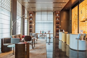 A modern hotel lobby with a reception desk, seating area, and decorative elements.