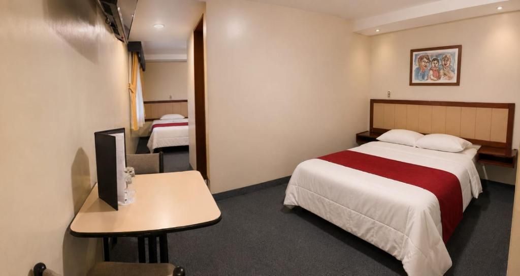 A hotel room with a single bed, a bedside table, a chair, a desk, and a television.