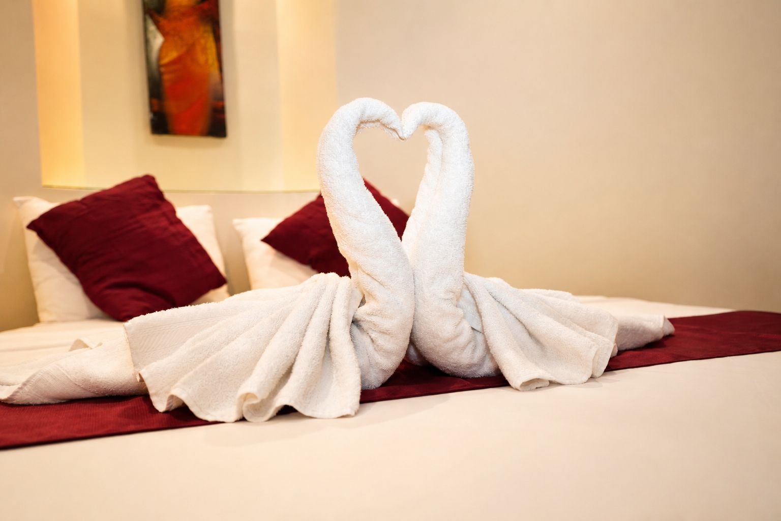 A bed with a white towel arranged in the shape of two swans.