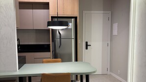Eine moderne Küche mit Einbaukühlschrank, einem Esstisch mit Stühlen und einer Pendelleuchte.