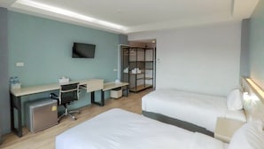 Ein Hotelzimmer mit Schreibtisch, zwei Betten, Fernseher und begehbarem Kleiderschrank.