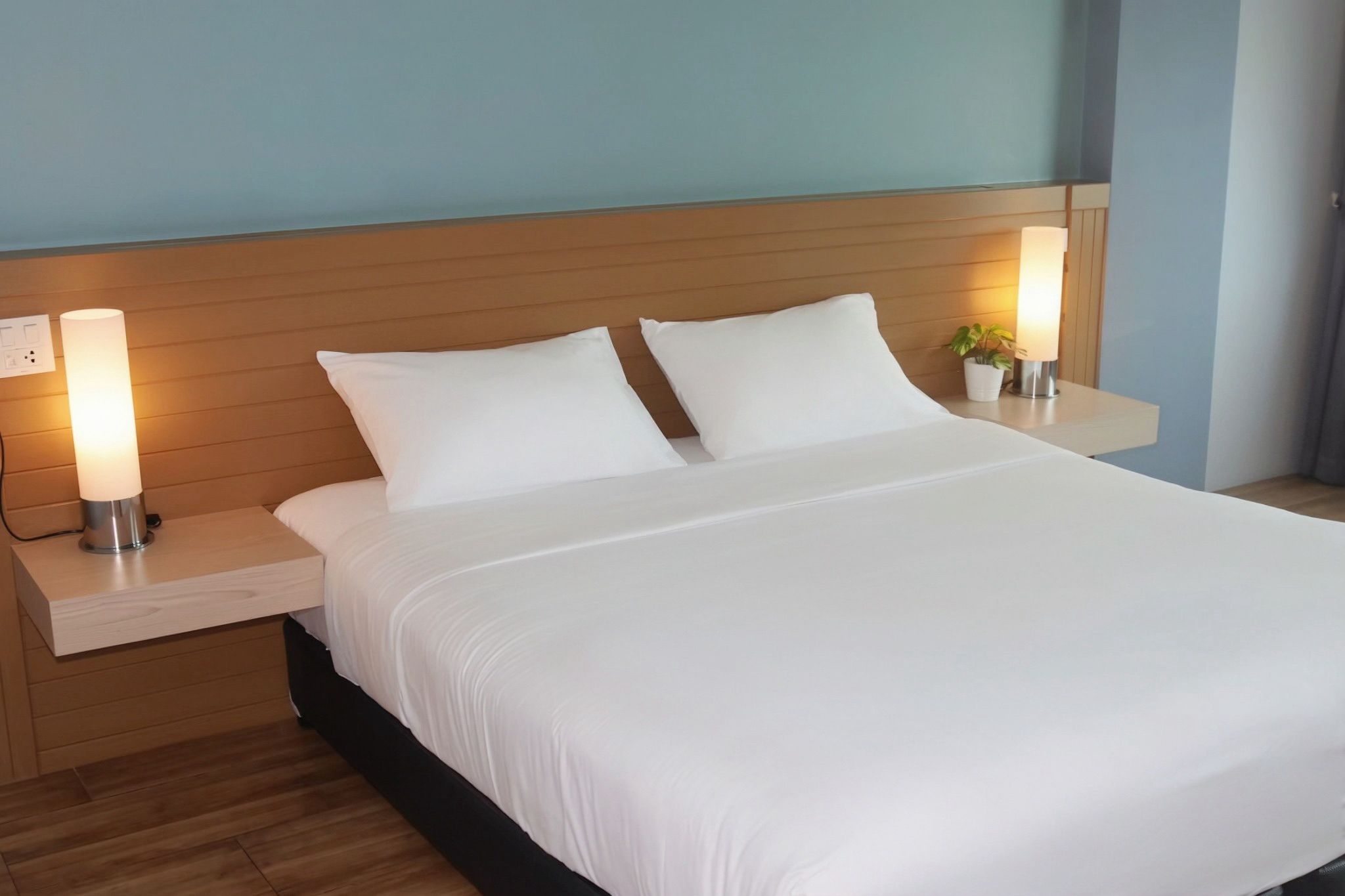 Una habitación de hotel con una cama, dos mesitas de noche y una mesita de noche con lámpara.