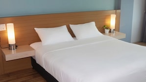 Ein Hotelzimmer mit einem Bett, zwei Nachttischen und einem Beistelltisch mit einer Lampe.