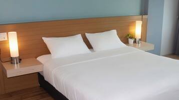 Una habitación de hotel con una cama, dos mesitas de noche y una mesita de noche con lámpara.