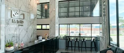 A hotel lobby with a reception desk, seating area, and large windows offering a view of the outside.