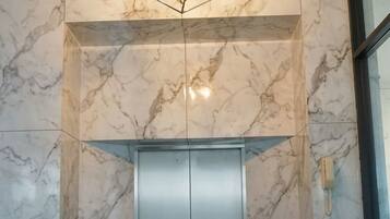 A modern elevator with marble walls and a geometric light fixture.