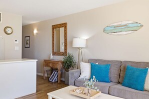 Ett vardagsrum med en soffa, ett soffbord, en lampa, en spegel och en väggklocka.