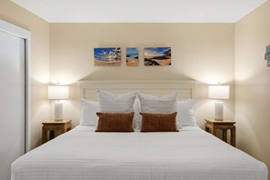 Ein Hotelzimmer mit einem großen Bett, zwei Wandlampen und zwei gerahmten Bildern darüber.