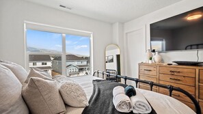 Ein Schlafzimmer mit Bett, Kommode, Spiegel und Fernseher.