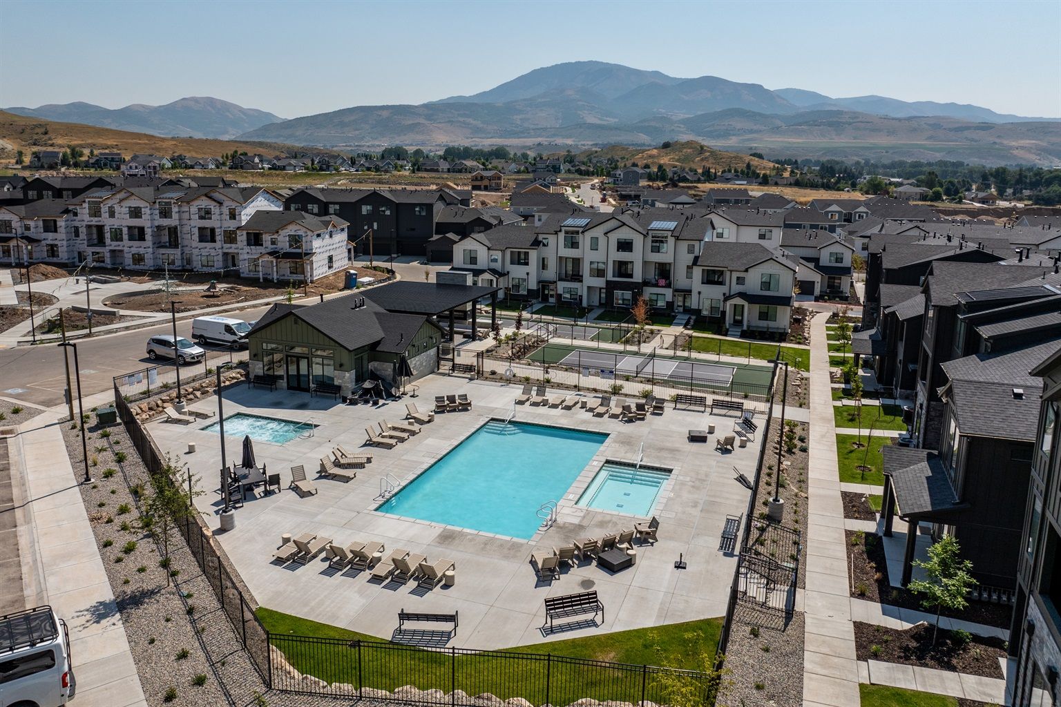 Un quartier résidentiel doté de deux piscines, de chaises longues et offrant une vue sur les montagnes.