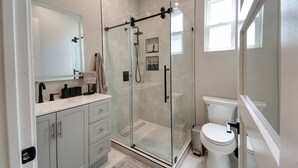 A modern bathroom with a glass-enclosed shower, a toilet, and a vanity with a mirror. - Modern 2BR/2BA Guest House in Granada Hills (Los Angeles)