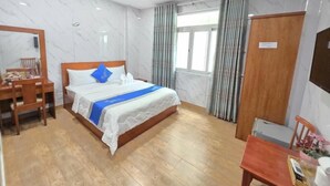 A hotel room with a bed, a desk, a chair, a wardrobe, and a window with curtains. - DŨNG INDIA HOTEL (Tân Bình)