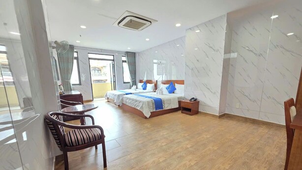 Una habitación de hotel con una cama grande, una zona de estar con una silla, una mesita y una mesita de noche.