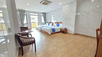 A hotel room with a large bed, a sitting area with a chair, a small table, and a bedside table.