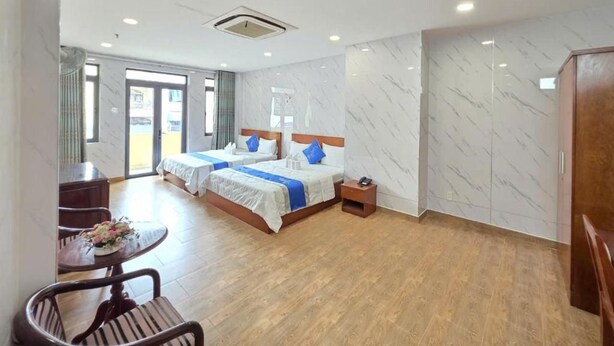 A hotel room with two beds, a dining table, and a small sitting area. - DŨNG INDIA HOTEL (Tân Bình)