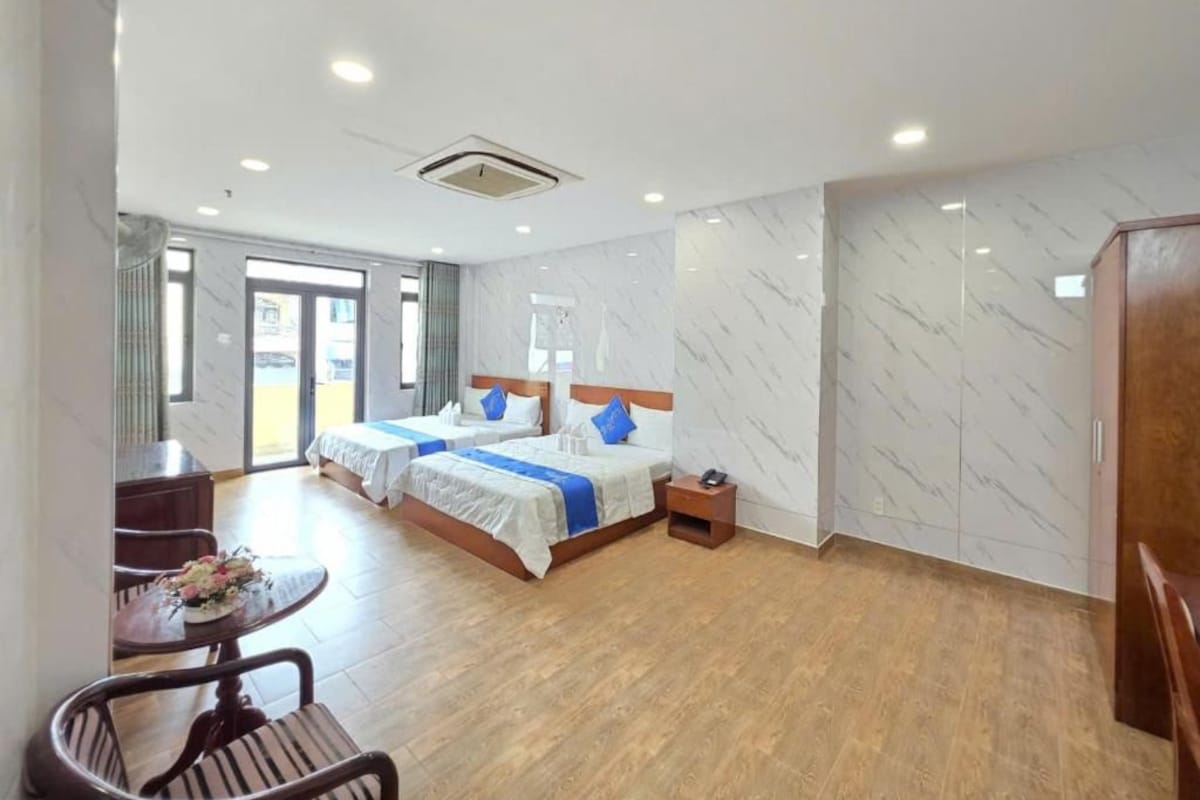 A hotel room with two beds, a dining table, and a small sitting area.