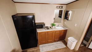 A compact kitchen with a refrigerator, microwave, sink, and cabinets. - 302 Lodging (Kermit)