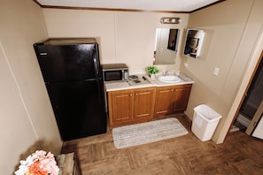 A compact kitchen with a refrigerator, microwave, sink, and cabinets. - 302 Lodging (Kermit)