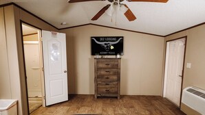 A bedroom with a bed, a ceiling fan, a dresser, and a sign on the wall. - 302 Lodging (Kermit)