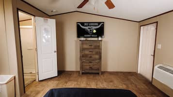 A bedroom with a bed, a ceiling fan, a dresser, and a sign on the wall.