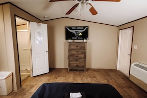 A bedroom with a bed, a ceiling fan, a dresser, and a sign on the wall. - 302 Lodging (Kermit)