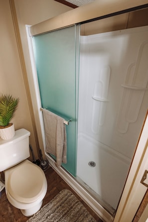 A bathroom with a toilet, a shower enclosure, and a small potted plant. - 302 Lodging (Kermit)