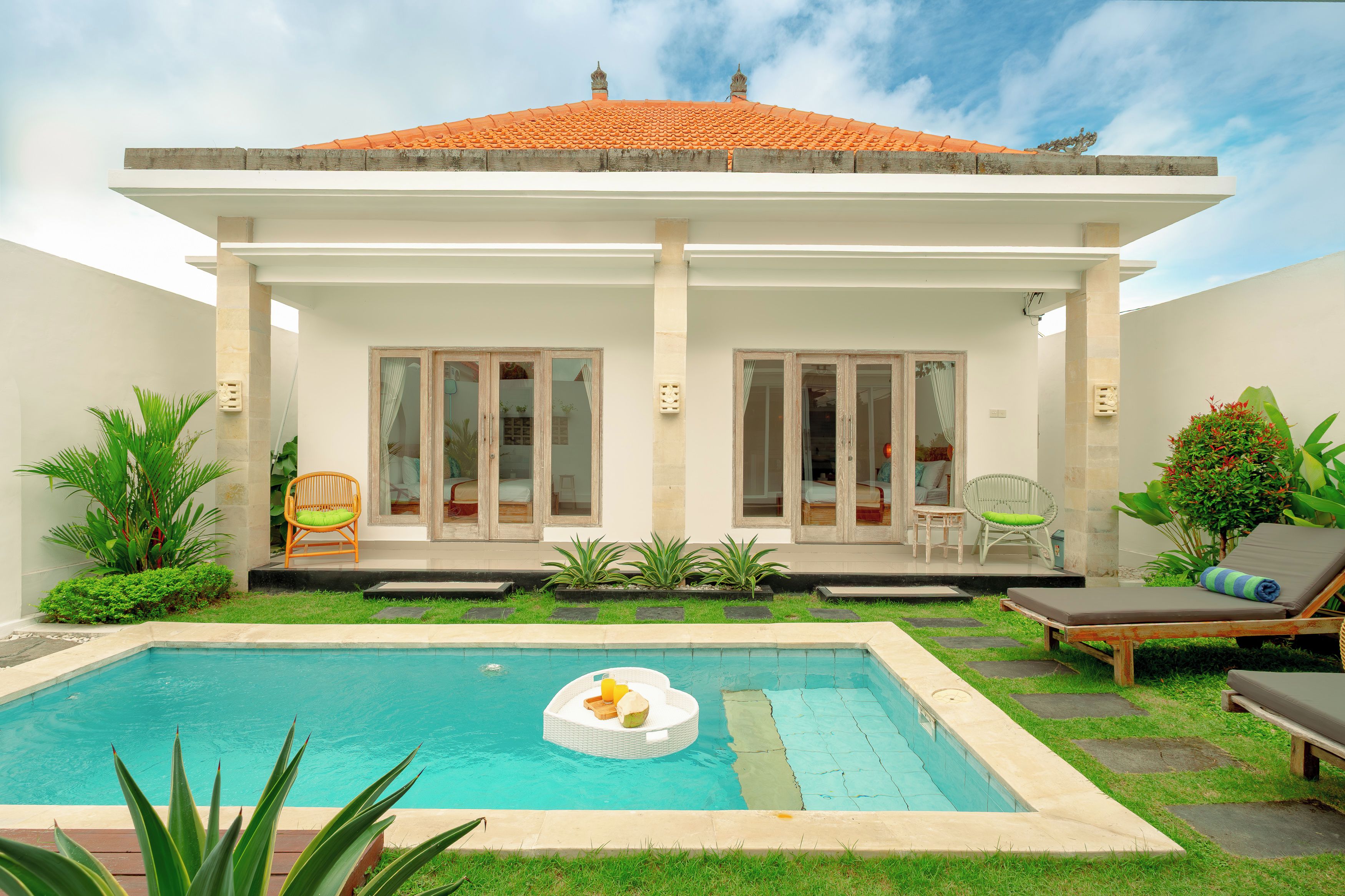 A two-story house with a swimming pool, outdoor seating, and a garden.