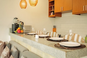 A modern kitchen with a granite countertop, a coffee maker, a blender, and a fruit bowl. - Villa Warna Canggu (Badung)