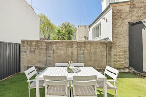 A patio with a white table and chairs, surrounded by a low brick wall and a grassy area. - Charming 4BR Surry Hills Terrace Walk to CBD (Surry Hills)