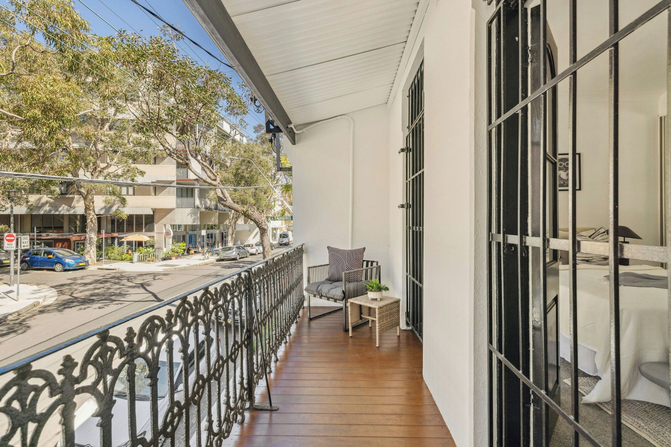A balcony with a wooden floor, a chair, and a table with a plant.