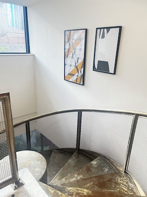 A staircase with metal railings and a glass balustrade, leading to an upper floor.