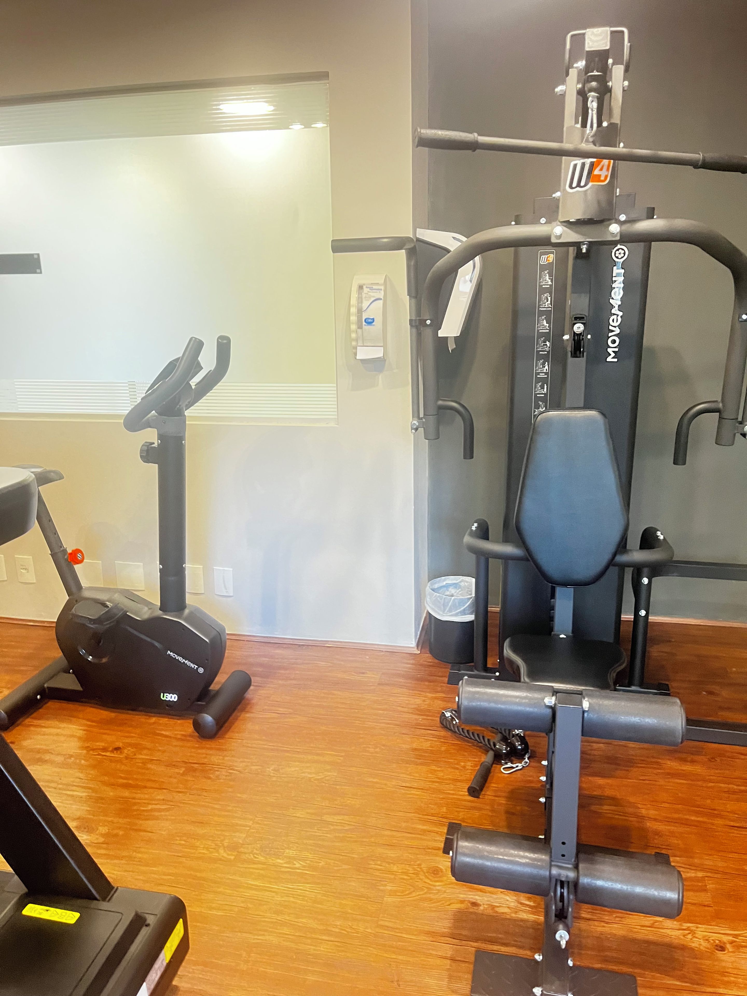 A gym with exercise equipment including a treadmill, elliptical, and weight machines.
