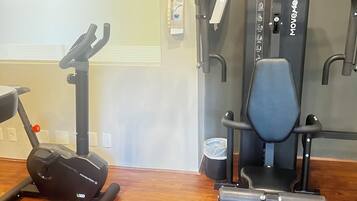 A gym with exercise equipment including a treadmill, elliptical, and weight machines.