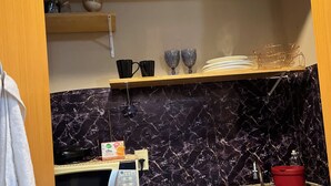 A compact kitchen with a microwave, sink, and wooden cabinets. - Cozy 1-bedroom bed & breakfast in peaceful São Paulo with AC (São Paulo)
