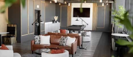 A modern lounge area with leather sofas, a pool table, and a flat-screen TV.