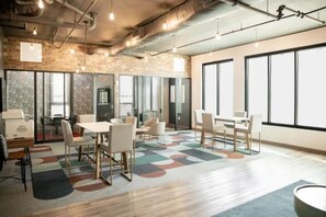 A modern office space with a large window, a meeting area with tables and chairs, and exposed ductwork on the ceiling. - Stylish Studio with Birmingham City Views C1 (Birmingham)
