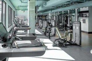 A gym with various exercise machines, including treadmills and weight stations, arranged in rows. - Stylish Studio with Birmingham City Views C1 (Birmingham)
