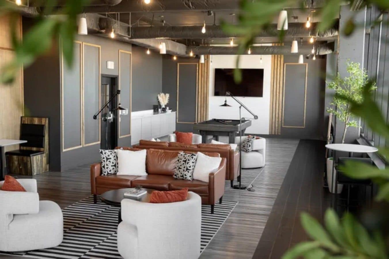 Un espace de détente moderne avec des canapés en cuir, une table de billard et un téléviseur à écran plat.