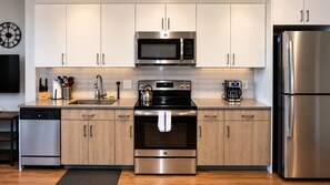 A modern kitchen with stainless steel appliances, wooden cabinets, and a tiled backsplash. - Stylish Studio with Birmingham City Views B1 (Birmingham)
