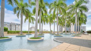 A pool area with palm trees and a building in the background. - Luxury Four seasons Hotel Miami 2 Bedroom Oceanview Luxury Suite. (Miami)