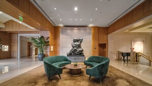 A lobby with two green armchairs, a central sculpture, and a patterned carpet. - Luxury Four seasons Hotel Miami 2 Bedroom Oceanview Luxury Suite. (Miami)