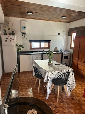 A compact kitchen with a dining table, a refrigerator, a stove, and a water heater. - Comfortable apartment with a pool in Playa del Carmen (Concepción del Uruguay)
