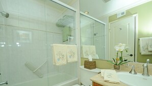 Een badkamer met een douchecabine van glas, een toilet, een wastafel met spiegel en handdoeken.