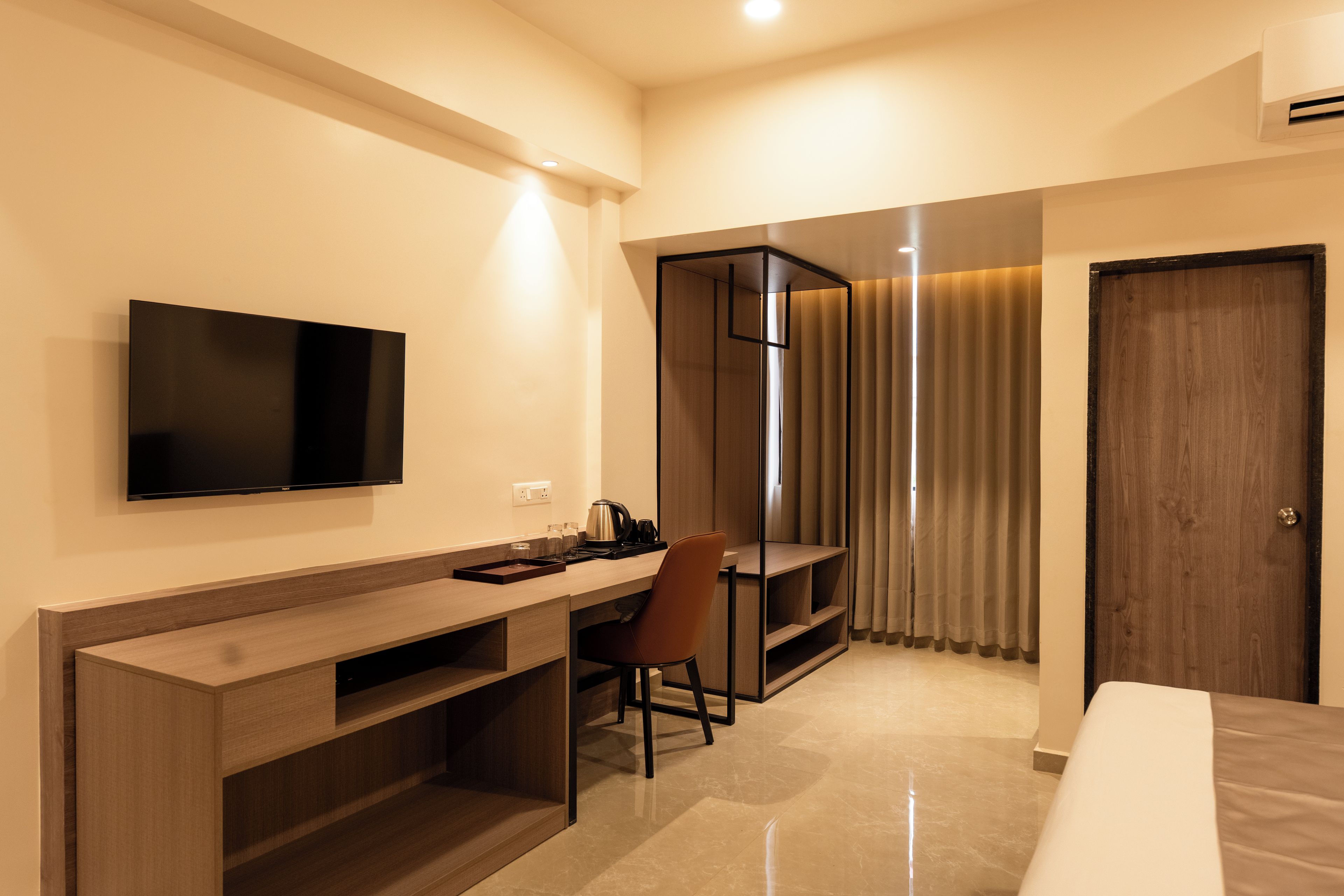 Una habitación de hotel con una cama, un escritorio con silla, un televisor y una puerta.