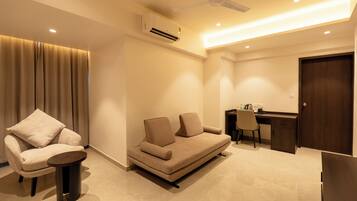 A modern living room with a sofa, a chair, a small table, a desk, and a ceiling fan.