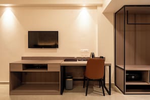 A modern office space with a desk, chair, and a mounted television.