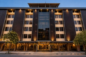 A modern hotel building with a glass facade, multiple floors, and a flat roof.