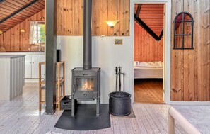 Um quarto acolhedor com lareira a lenha, uma cama e um pequeno espaço de cozinha.