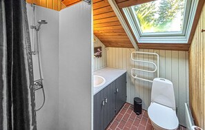 Ein kleines Badezimmer mit einer Dachfenster, einer Dusche, einer Toilette und einem Waschbecken.